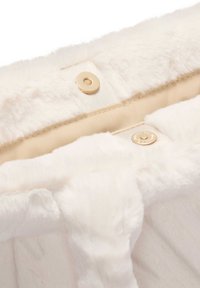 Biała tkanina faux fur o miękkiej fakturze, z beżową podszewką i złotymi guzikami. Wzór zawiera zapięcie na zatrzask.