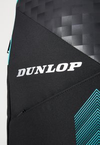 Dunlop Tennistasche aus schwarzem Stoff mit einem strukturierten schwarzen Panel. Sie hat aquablau diagonale Streifen und den Markennamen in fetter weißer Schrift.