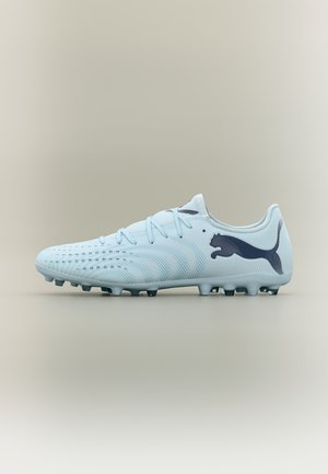 Šviesiai mėlynas Puma futbolo batelio modelis su juodu logotipu, tekstūruotu viršumi, raišteliais ir įspraustais pado kuokšteliais, parodytas iš šono neutraliame fone.