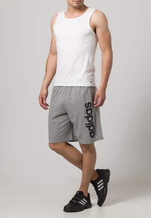 Camiseta blanca sin mangas, pantalones cortos deportivos grises con logo negro de "adidas" y zapatillas deportivas negras. Tejido liso, ajuste relajado, diseño casual.