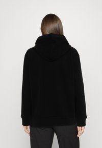 Svart hoodie i mjukt tyg, med en stor huva, långa ärmar och en avslappnad passform, med ribbade mudd och nederkant.