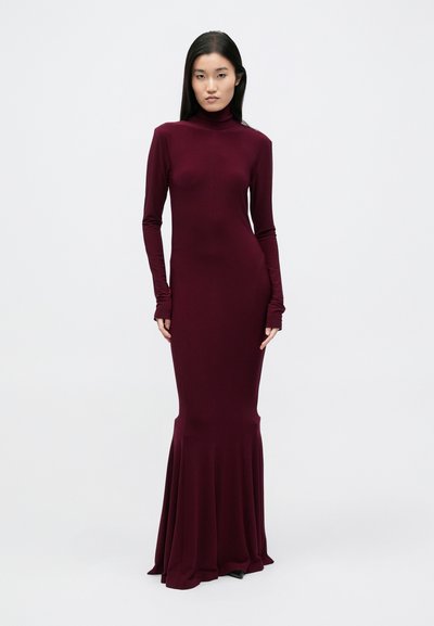 Pikad varrukad, liibuv kleit sügavbordoopunasest venivast kangast, millel on kõrge poolkaelus ja hõljuv alt äär, et rõhutada vooluvaid jooni.