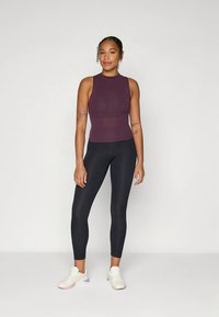 Vinrød ribbet tanktop med høj hals, kombineret med sorte leggings og hvide sneakers med lilla detaljer.