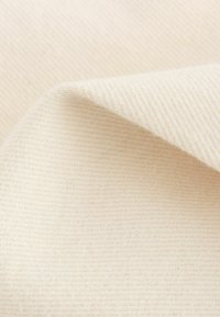 Crème-kleurige stof met een gladde textuur, die een subtiel diagonaal weefpatroon en een lichte glans vertoont. Zacht en buigzaam.