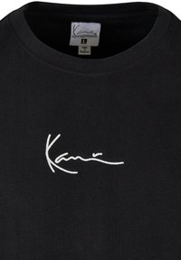 Black cotton t-shirt with a round neckline featuring white embroidered signature logo on the left chest area. Size label L visible.