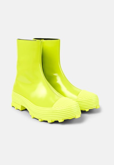 Neon yellow waterproof ankle boots with a textured rubber sole, round toe, and vertical zipper for easy wear and a modern design.