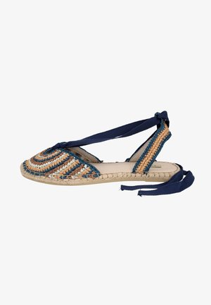 Sandalia plana tipo esparto con parte superior tejida multicolor y cordones azul marino en el tobillo sobre suela beige, vista lateral.
