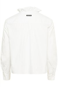 Hvid bluse med lange ærmer, høj flæsekant, knaplukning ved ærmekanterne og "IW.EDITION" mærke øverst på ryggen.