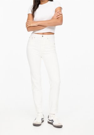 Pantalones de mezclilla blanca con corte ajustado y cintura alta, con cierre frontal de botón y cremallera, bolsillos traseros y detalles de costura mínimos.