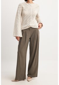 Pitkähihainen, kerma-valkoinen neulepusero, jossa on kalanruotokuvio, yhdistetty korkeavyötäröisiin, väljälahkeisiin oliivinvihreisiin housuihin ja beigen värisiin teräväkärkisiin balleriinoihin.