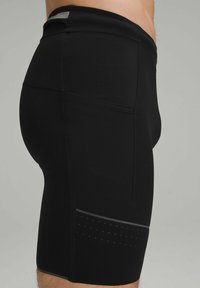 Sorte atletiske shorts lavet af strækbart materiale; tætsiddende design med sidelomme og reflekterende streg; tekstureret taljebånd med prikket mønster i kanten.