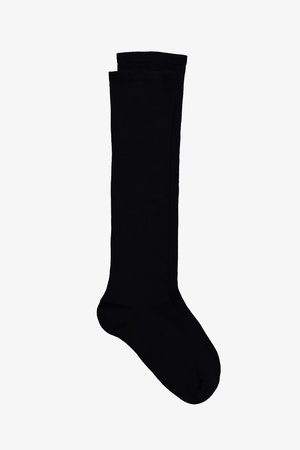 Une chaussette noire montante jusqu'au genou, posée à plat avec la partie du pied légèrement inclinée vers la droite sur un fond blanc.