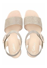 Sandali beige con una larga fascia glitterata e una cinghia alla caviglia di supporto dotata di fibbia. Soletta morbida con il marchio al centro.