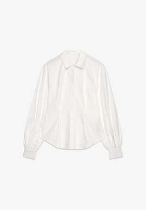 Valge pika varrukaga särk, mis on valmistatud puuvillast. Särgil on klassikaline kaelus, nööbiga eesmine sulgemine ja volangvarrukad, mis tagavad mugava istuvuse.