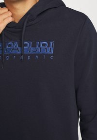 Felpa con cappuccio di colore blu navy, realizzata in tessuto morbido. Presenta un logo blu ricamato, cordoncino al collo e una vestibilità rilassata.