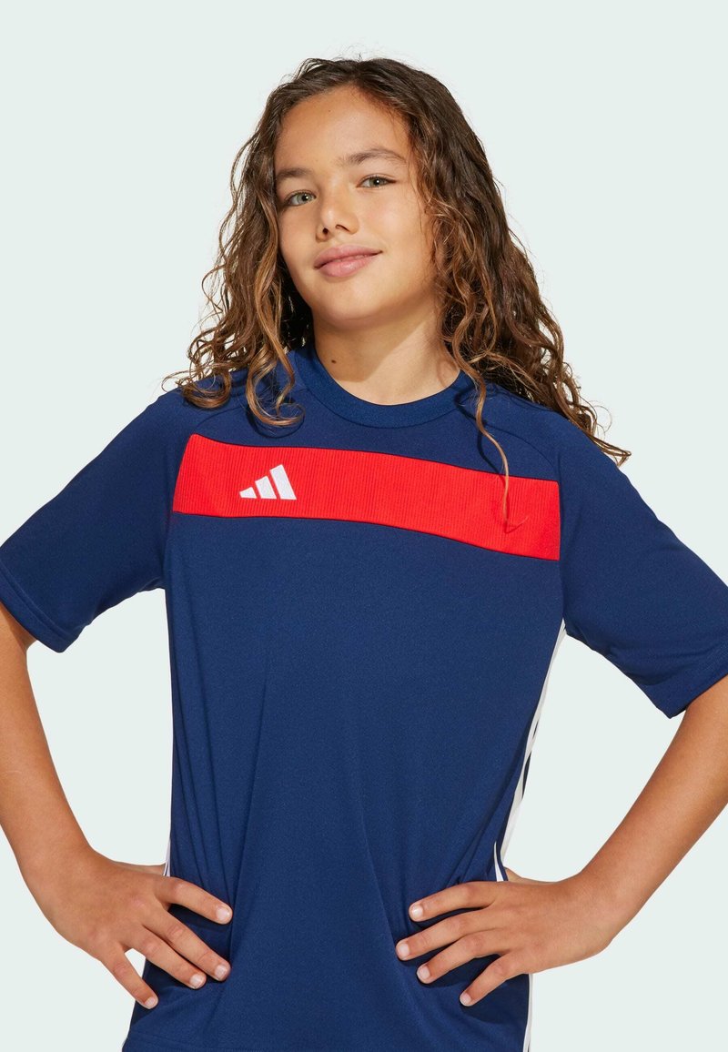 Námořnické sportovní tričko s červeným vodorovným panelem, bílým logem Adidas, krátkými rukávy a hladkým, prodyšným materiálem.