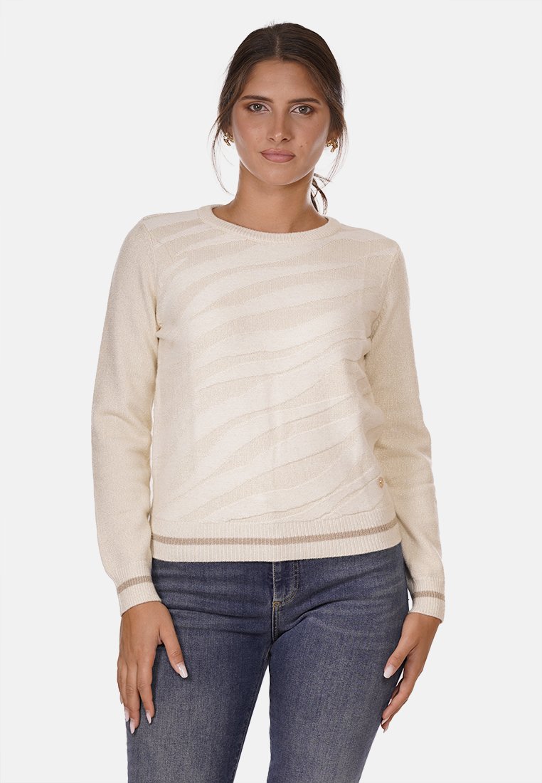 Maglione color crema con motivi a onda testurizzati, scollatura rotonda, maniche lunghe e orlo a costine. Abbinato a jeans blu scuro.