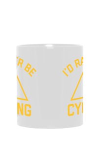 Taza de cerámica blanca con texto amarillo; dice "Preferiría estar en bicicleta" y tiene un diseño triangular. Superficie suave, forma cilíndrica.
