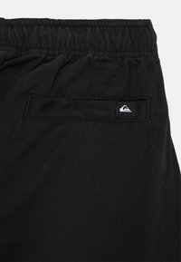 Svarta byxor med elastisk midja och ett bakficka med en liten svart och vit Quiksilver-logotagg.