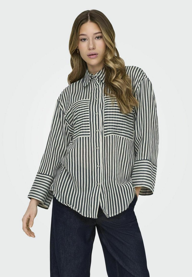 Camisa de botones a rayas en beige y verde oscuro. Cuenta con un collar, mangas largas y dos bolsillos en el pecho. Textura de tela suave y ligera.