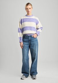 Striped pullover sweater in cream with lavender bands, made of textured knit. Paired with light blue high-waisted wide-leg jeans.