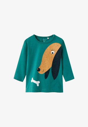 Camiseta de manga larga color verde azulado con la imagen de una cara de perro de dibujos animados en diseño marrón y negro, acompañada de un gráfico de un hueso blanco en la parte inferior.