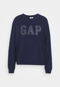 Námořnicky modrá mikina s kulatým výstřihem, s vystouplými třpytivými písmeny "GAP" na přední straně a žebrovanými manžetami.
