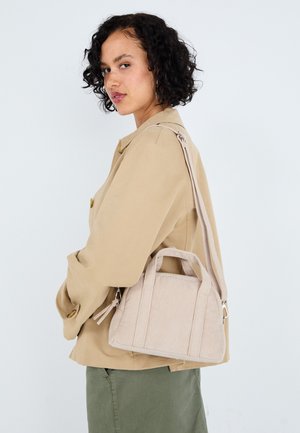 Bolso de mano de cuerda beige con asas dobles y una correa de hombro ajustable, que presenta una superficie texturizada y detalles de costura sutiles.