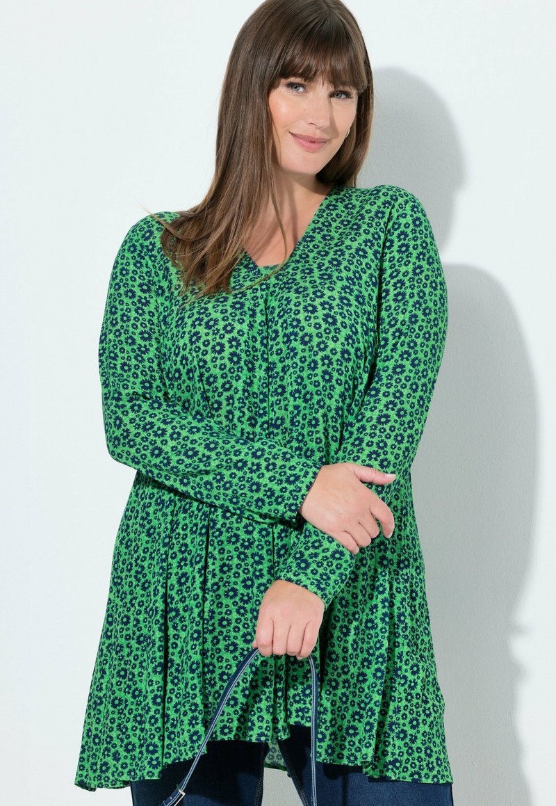 Vestito tunica verde con maniche lunghe, caratterizzato da un motivo floreale in verde più scuro. Il design include un fondo svasato e una scollatura a V.