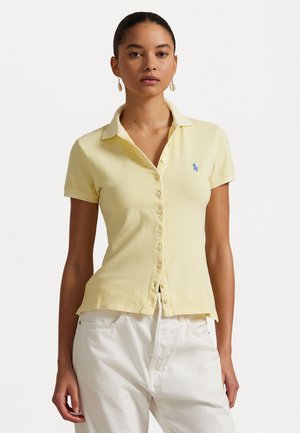 Geel polo shirt van getextureerde stof, met een knoopsluiting aan de voorkant, korte mouwen en een klein blauw logo op de linkerkant van de borst.