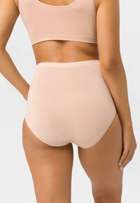 Beige hochgeschnittene Shorts mit nahtlosem Design, glatter Textur und breitem Bund. Mit einem dezenten, geschwungenen Saum an den Beinausschnitten.