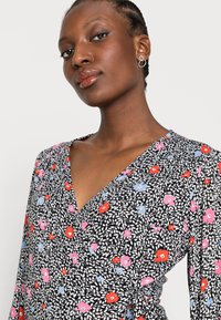Vestido envolvente floral com base preta, flores vibrantes em vermelho, rosa e azul, com um decote em V profundo e um padrão sutil de folhas.