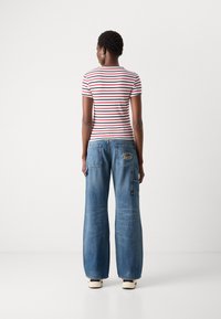 T-shirt à manches courtes rayé en rouge et bleu marins sur une base blanche, associé à un jean bleu à jambes larges avec poches brodées.