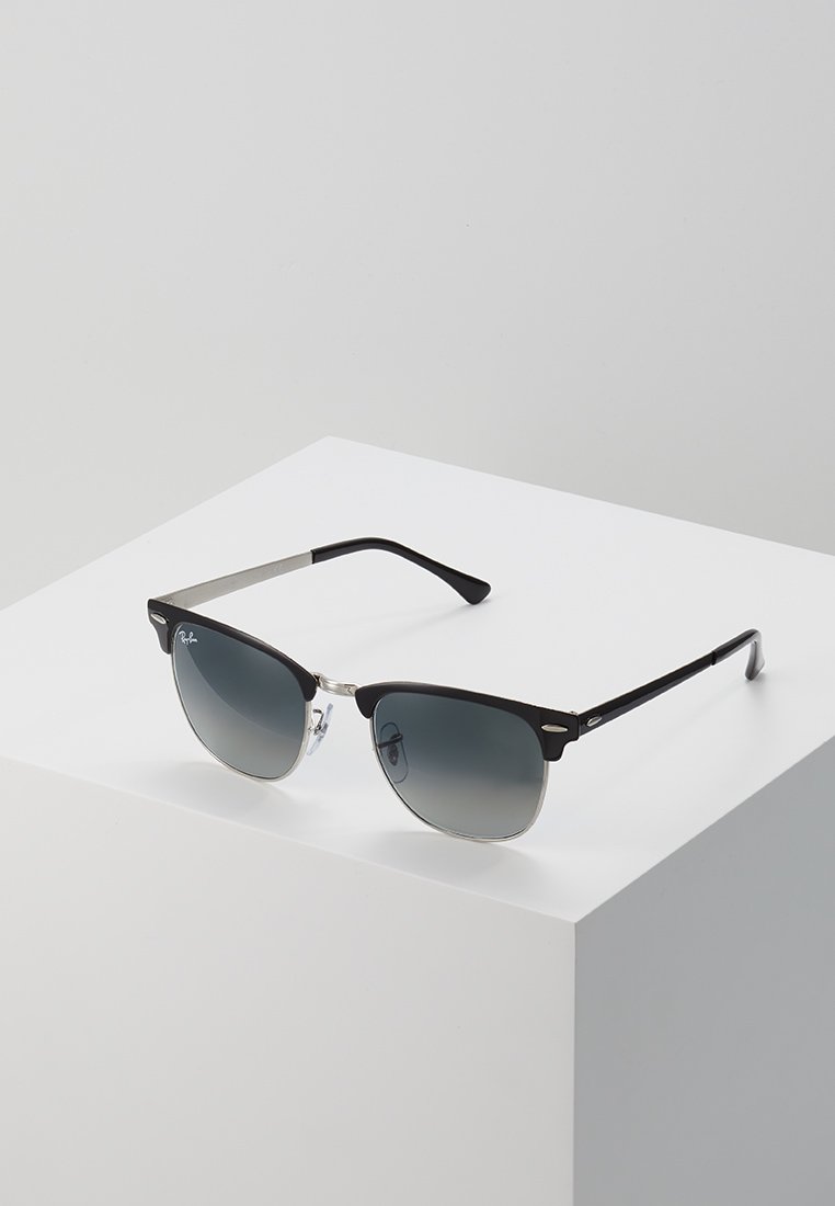 Ochelari negri cu lentile gri degradat, accente metalice și brațe din plastic elegante. Designul are o formă modernă de tip cat-eye.