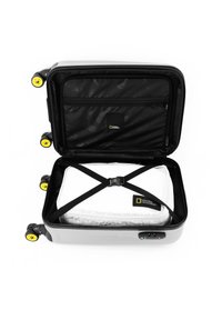 Gray hard-shell suitcase with yellow wheels, unzipped to reveal a white packing cube secured with black straps and a patterned interior.
