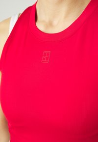 Rotes, geripptes Sporttanktop mit runder Ausschnitt und einem dezenten, eingeprägten Logo. Verfügt über eine glatte Textur und eine taillierte Passform.