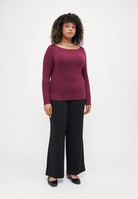 Maroon long-sleeve top with a modest neckline, paired with high-waisted black wide-leg pants and black flats, set against a plain white background.