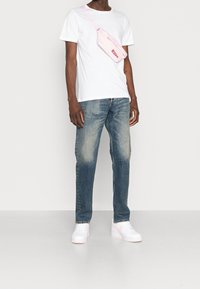 Valkoinen lyhythihainen t-paita, haalistuneet siniset farkut ja vaaleanpunainen vyölaukku. Valkoiset tennarit, joissa vaaleanpunaiset yksityiskohdat. Yksinkertainen, rento asu.