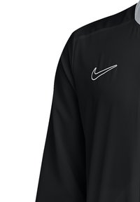 Black Nike jacket with a quarter zip, long sleeves, and textured fabric. Features a white Nike logo on the left chest. Simple design.