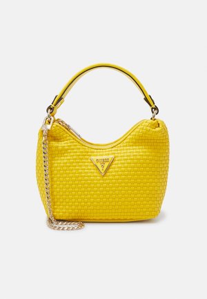 Bolso de hombro de cuero trenzado amarillo con correa de cadena dorada y logotipo triangular de Guess en la parte frontal, orientado hacia adelante sobre un fondo blanco.