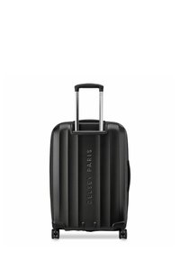 Valise noire à coque rigide avec texture rainurée verticale, poignée télescopique et quatre roulettes pivotantes. Présente le logo embossé "DELSAY PARIS".