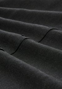 Black fabric with a smooth texture, featuring stitched lines and slight folds. The material appears lightweight and versatile.