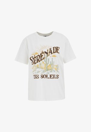 Balta kokvilnas T-krekls ar vaļēju piegriezumu, uz kura ir grafiskais attēls ar kaktusiem un sauli, kā arī teksts "SÉRÉNADE DES SOLEILS" brūnā un dzeltenā krāsā.
