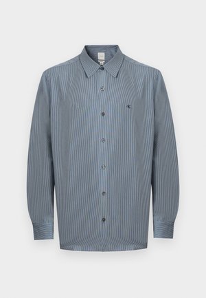 Chemise à manches longues pour homme, boutonnée, de couleur bleue avec un motif à carreaux subtil et un petit logo "ck" brodé sur la poitrine.