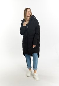 Geacă puf din negru cu fermoar în față, glugă și două buzunare frontale. Are un finisaj lucios și o croială lejeră, purtată cu pantaloni din denim deschis.