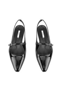 Chaussures slingback en cuir verni noir avec un bout pointu, une bride ajustable à la cheville et une texture lisse. Marque visible sur la semelle intérieure.