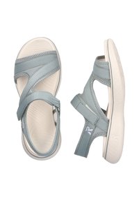 Light blue sandals made of fabric with cross straps, a cushioned footbed, and a textured beige rubber sole, featuring a logo on the side.