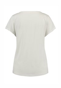 Camisa corta de manga corta beige claro con un escote amplio y una textura suave. Presenta un corte relajado sin patrones ni acentos visibles.