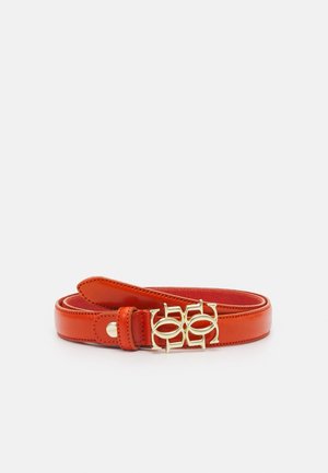 Ceinture en cuir rouge avec des bords cousus et une boucle double ovale dorée sur fond blanc.