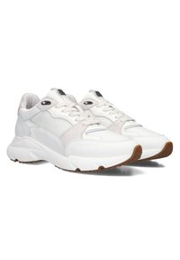 White sneaker with a textured upper combining mesh and suede. Features a cushioned sole, laces, and black hardware accents. Rubber outsole.